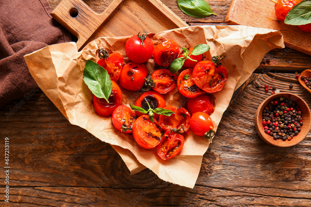 Board with tasty grilled tomatoes and basil on wooden background