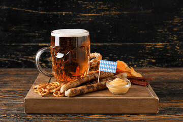 Mug of cold beer and different snacks on wooden background. Oktoberfest celebration