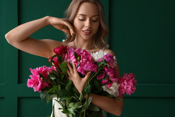 Poster - Young woman with beautiful peony flowers near green wall