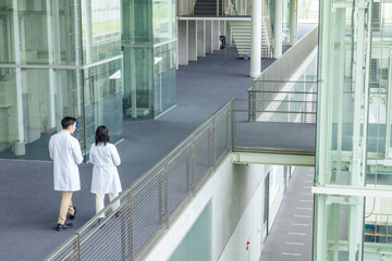Poster - Multinational group walking in the lobby wearing white coats.