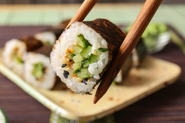 Wall Mural - Chopsticks with tasty maki roll, closeup view