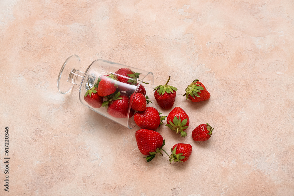 Glass with fresh strawberries on pink background