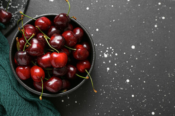 Bowl with sweet cherries on black background