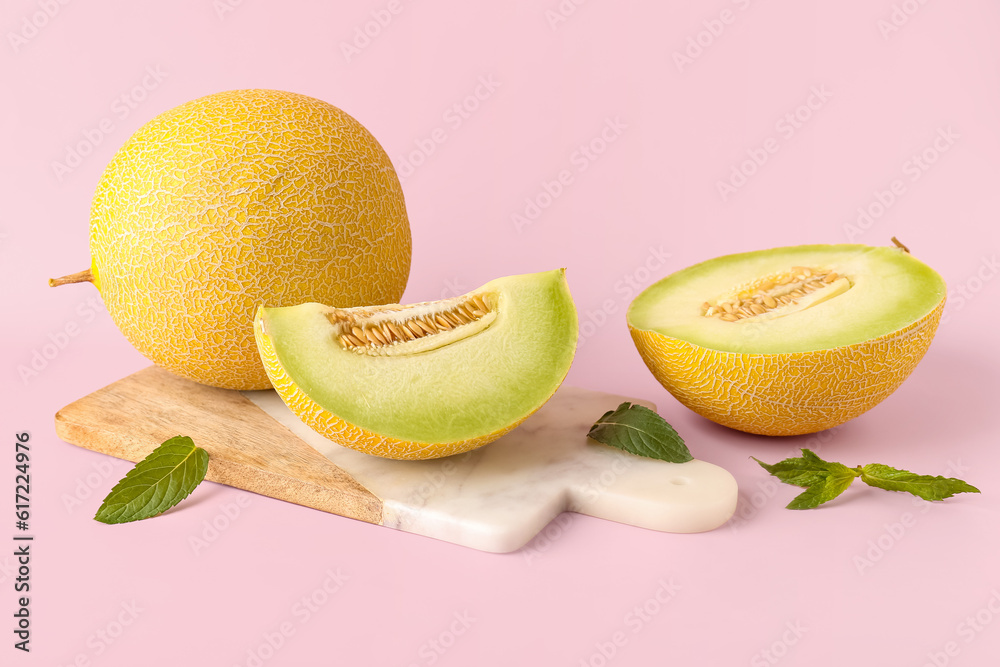Board with half of sweet melon and piece on pink background