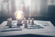 © Charnchai saeheng - light bulb represents good idea center of The wooden doll represents the employee of the company on financial, budget or asset document in workplace. Security, save,  Corporation, Enterprise concept.