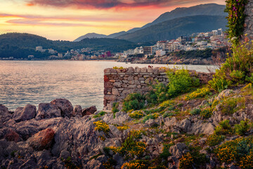 Wall Mural - Blooming flowers on the shore of Adriatic sea in Himare town. Amazing sunset in Albania, Europe. Traveling concept background.
