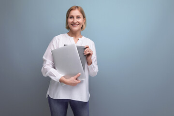 serious mature business woman with blond hair works on internet using laptop