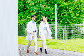 Poster - A multinational group wearing a white coat and walking through a outdoor facility