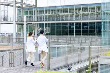 Poster - A multinational group wearing a white coat and walking through a facility.