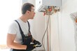 Gas engineer checking and cleaning a boiler during the inspection at home