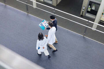 Poster - A multinational group having a conversation in the lobby.
People in white coats and sales staff. High angle view.