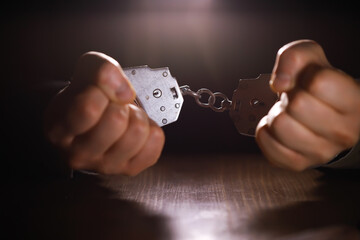 stressed out businessman hands bothered with handcuffs suffering at custody for concept of suspiciou