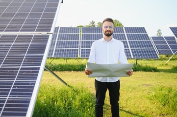 Solar power plant. Man standing near solar panels. Renewable energy.