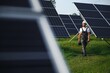 © Serhii - a worker walks through a solar panel farm