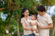 © geargodz - happy family in park. father and mother talking and playing with infant baby.