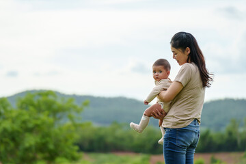 happy mother holding her infant baby in green mountain