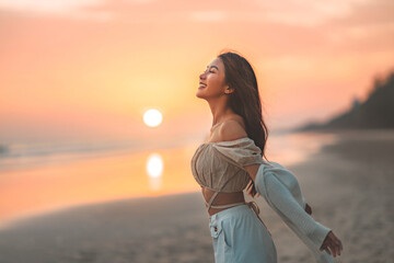 Wall Mural - Side view of young asian woman with freedom on the sea beach at golden sunset, Female tourist on seaside summer vacation, Go Everywhere.