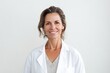 © igolaizola - Portrait of smiling mature female doctor standing against white background in medical office