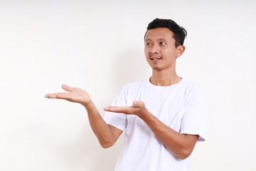 Wall Mural - Asian funny man standing while presenting something beside him. Isolated on white with copyspace