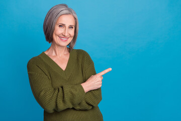 Sticker - Photo of good mood positive woman bob hairstyle dressed khaki sweater directing at offer empty space isolated on blue color background