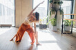 © muse studio - Beautiful pose asana woman workout trainer yoga body exercises in a fitness club with plants and a large window the light is sunny.