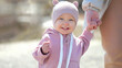 © lenblr - Excited toddler enjoys walking and holding mother hand at resort. Toddler girl with amused expression smiles and laugh during walking