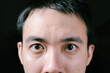 © David - Close-up shot of the partial face of a young Asian man that has huge eyes. Isolated black background.