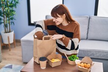 Young Woman Holding Take Away Food Of Paper Bag At Home