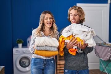 Canvas Print - Young couple doing laundry winking looking at the camera with sexy expression, cheerful and happy face.