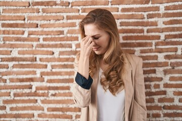 Poster - Beautiful blonde woman standing over bricks wall tired rubbing nose and eyes feeling fatigue and headache. stress and frustration concept.