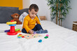 © Krakenimages.com - Adorable hispanic boy playing with maths puzzle game sitting on bed at bedroom