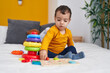 © Krakenimages.com - Adorable hispanic boy playing with maths puzzle game sitting on bed at bedroom