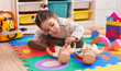 © Krakenimages.com - Adorable hispanic girl sitting on floor playing with baby doll at kindergarten