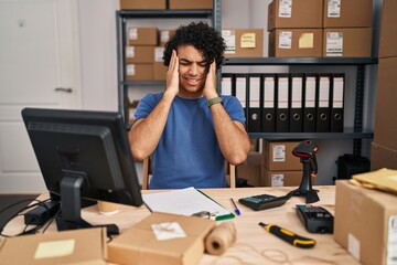 Wall Mural - Hispanic man with curly hair working at small business ecommerce with hand on head, headache because stress. suffering migraine.