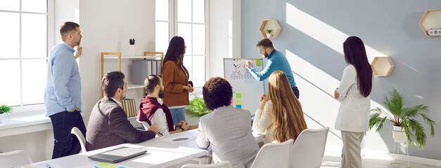 Brainstorming. Business man explaining new business project plan to team at business meeting in office. Startup team brainstorms business ideas together. Web banner.