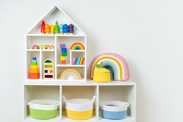 Wall Mural - White shelving with rainbow wooden toys and colorful storage baskets. Interior design. Organizing and storage ideas in nursery.