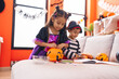 © Krakenimages.com - Adorable boy and girl having halloween party holding candies at home