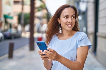 Wall Mural - Young woman smiling confident using smartphone at street