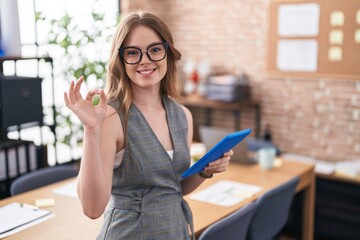 Poster - Caucasian woman working at the office wearing glasses smiling positive doing ok sign with hand and fingers. successful expression.