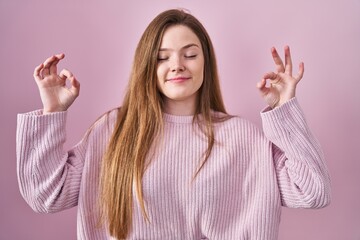 Poster - Young caucasian woman standing over pink background relaxed and smiling with eyes closed doing meditation gesture with fingers. yoga concept.