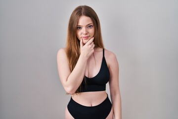 Poster - Young caucasian woman wearing lingerie looking confident at the camera with smile with crossed arms and hand raised on chin. thinking positive.