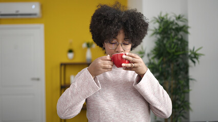 Poster - Young african american woman drinking tea sitting on sofa at home