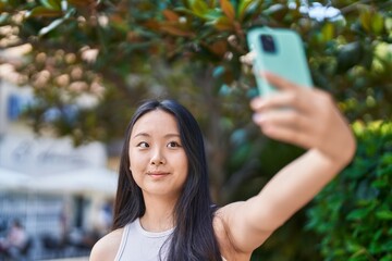 Canvas Print - Young chinese woman smiling confident making selfie by the smartphone at park