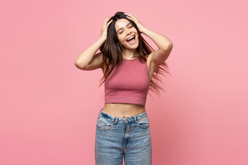 Wall Mural - Portrait of smiling teenage girl with long hair, closed eyes standing isolated on pink background