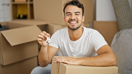 Young hispanic man smiling confident holding new house keys at new home