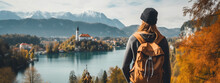 Young Girl With Backpack In Hat Stands On Top Of Cliff On The Shore Of Lake Looking Into The Distance At Old Castle Of Bled. Close-up. Generative Ai Content