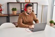 © Krakenimages.com - Young hispanic man listening to music and dancing sitting on table at home