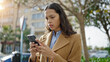 © Krakenimages.com - Young beautiful hispanic woman using smartphone with serious face at park