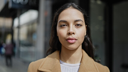 Young beautiful hispanic woman standing with serious expression at street