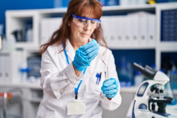 Sticker - Middle age woman scientist measuring liquid at laboratory